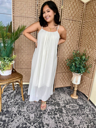 Cream boho flowy midi dress with thin straps and relaxed silhouette on model.
