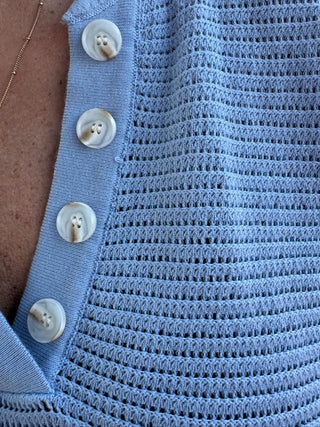 Sky blue textured knit top with mother-of-pearl buttons and open weave pattern detail.
