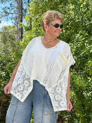 White lace handkerchief top with floral cutout details and sheer fabric overlay.
