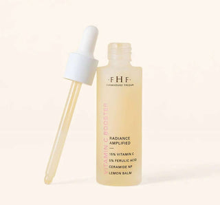 FHF Vitamin C Booster Radiance Amplified serum bottle amid fresh citrus slices for glowing skin boost.
