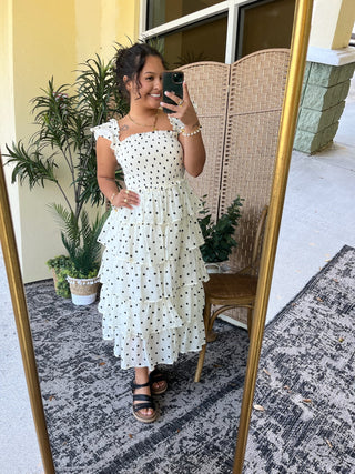 White midi dress with black polka dots and short ruffle sleeves.
