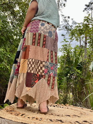 Patchwork maxi skirt with mixed floral and geometric prints in burgundy, cream, and tan with scalloped hem.

