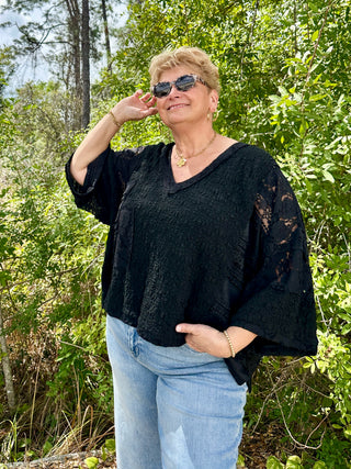 Black lace handkerchief top with three-quarter sleeves and textured fabric detail.
