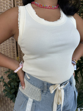 White ribbed knit tank top with lace trim neckline and armholes.
