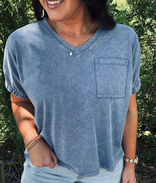 Denim Blue Mineral Washed Cap Sleeve Pocket Top on hanger, showcases soft texture and casual style in a versatile garment.