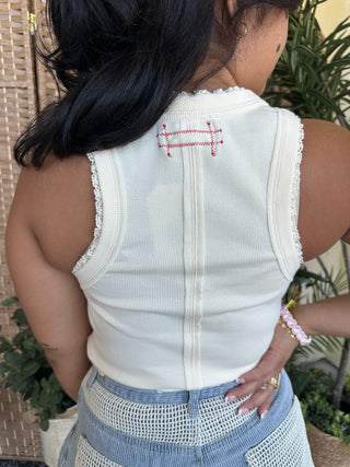 White ribbed knit tank top with red cross-stitch embroidery design and lace trim edges.
