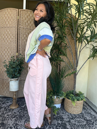 Oversized dolman top with green and white stripes, blue ribbed trim on short sleeves, paired with light pink pants.
