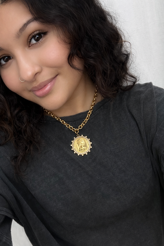 Black crew neck sweatshirt with gold chain coin pendant necklace.
