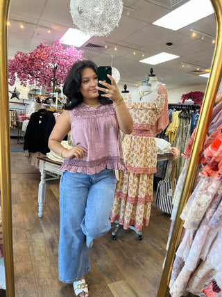 Lavender pink sleeveless top with ruched detail worn with blue jeans in store mirror.
