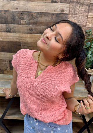 Pink ribbed short-sleeve sweater with split V-neckline, relaxed fit.
