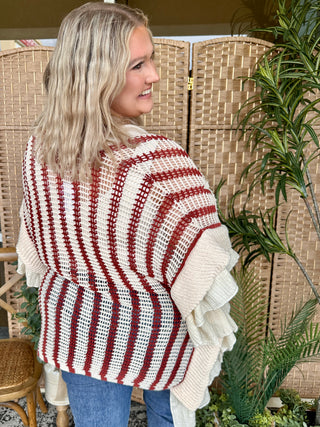 Cream and burgundy striped knit vest with ruffled short sleeves over white long-sleeve top.
