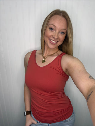 Burnt sienna sleeveless tank top with ruched sides on model against white background.
