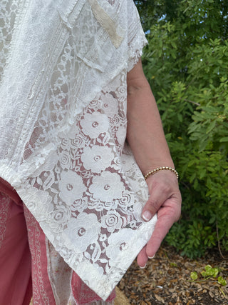 Ivory lace beachy top with floral pattern and handkerchief hem detail.
