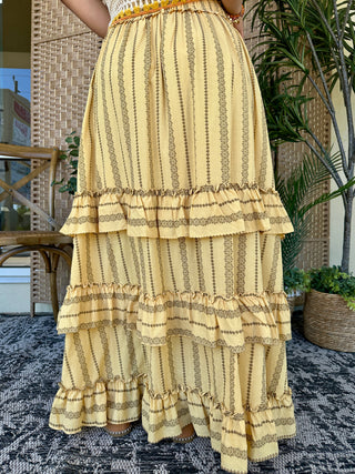 Cream maxi skirt with olive vertical striped pattern and tiered ruffle hem with gold trim detail.
