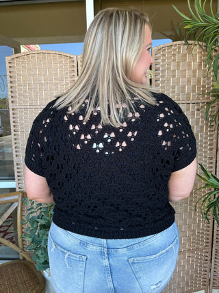 Black open weave short-sleeve sweater top with textured knit pattern and cutout details.
