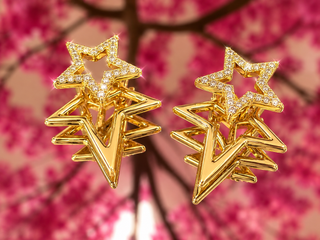 Gold star-shaped layered earrings with pave stones and metallic finish.
