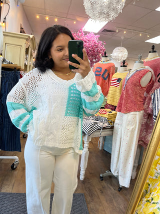 Cream, turquoise and white color block open weave sweater with long sleeves on model in boutique.
