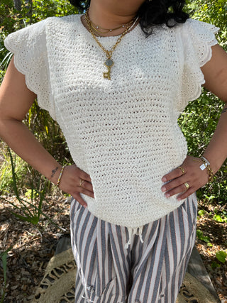White eyelet short-sleeve top with ruffled edges and open knit texture.
