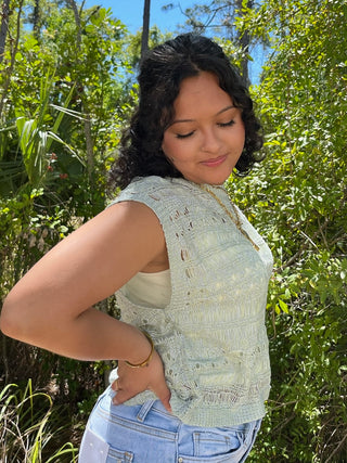 Cream crochet sleeveless top with textured knit pattern and cutout details.
