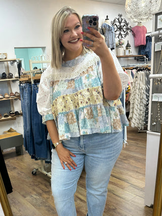 Ivory and blue tiered floral top with lace trim and patchwork color blocking in cream, blue, and yellow tones.
