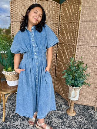 Light blue mineral washed denim button-down midi dress with short puffed sleeves and pleated skirt.
