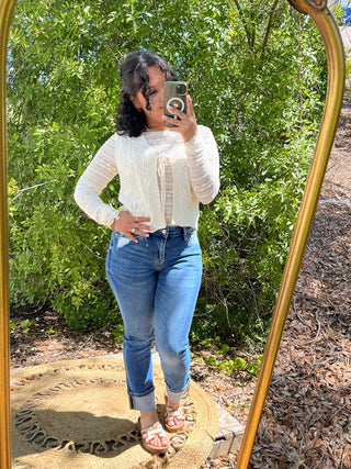 Medium wash straight leg jeans with cuffed ankles and mid-rise fit, paired with white textured long-sleeve top.
