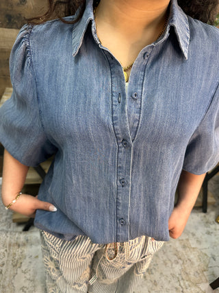Blue chambray button-down shirt with short puffed sleeves and collar detail.
