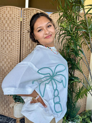 White oversized cotton terry top with green rope palm tree embroidery on back.
