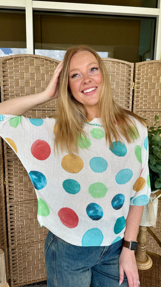 Cream batwing top with multicolored polka dots in red, blue, green, and yellow.
