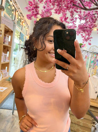 Blush pink ribbed knit tank top with round neckline on model.
