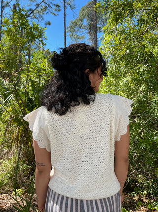 Cream eyelet short-sleeve top with ruffled cap sleeves and textured knit fabric.
