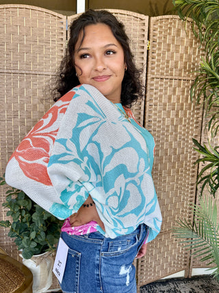 Coral Reef Batwing Top in turquoise, coral, and white abstract marble print with textured knit fabric.
