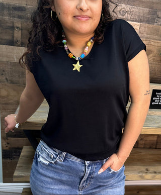 Black cap sleeve v-neck knit top styled with colorful beaded necklace featuring gold star pendant.
