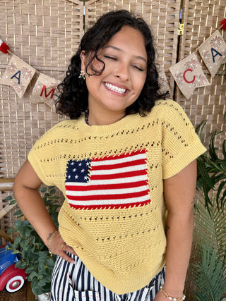 Yellow knit short-sleeve top with American flag graphic and textured cable pattern detail.

