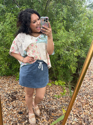 Blue denim skort with white drawstring waist, styled with floral print top.

