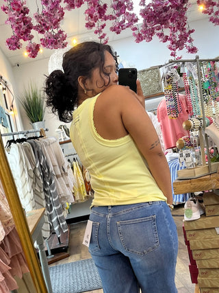 Lemon yellow ribbed knit tank top with scoop neckline on model in boutique setting.

