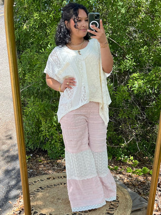 Ivory lace handkerchief top with asymmetrical hem paired with pink and white lace flare pants.
