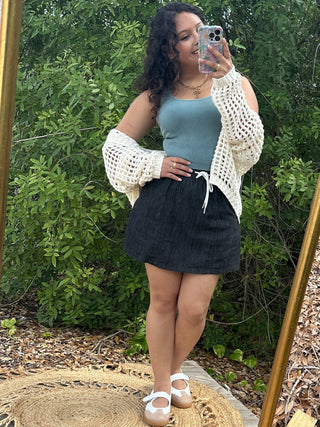 Cream crochet cardigan with textured open-knit pattern and puffed sleeves worn over blue ribbed tank.
