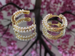 Gold mini huggie hoop earrings adorned with pearl beads, displayed as a pair.
