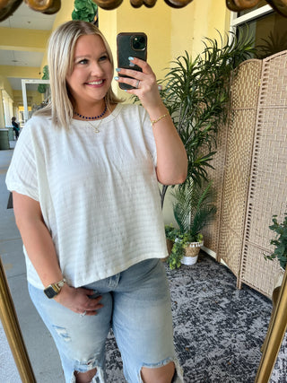 White textured short-sleeve dolman top with crew neckline, relaxed fit design.
