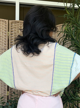 Oversized dolman top with multicolor horizontal stripes in coral, yellow, and blue with blue trim detail.
