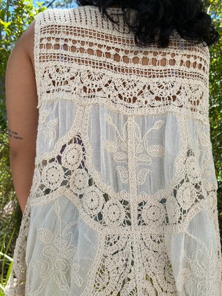 Cream crochet sleeveless vest top with intricate floral lace patterns and geometric cutouts throughout.
