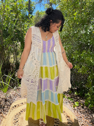 Cream crochet open vest over colorblock dress with purple, blue, and lime striped pattern.
