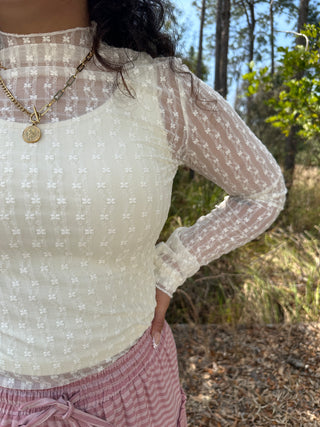 Ivory mesh long sleeve top with white floral embroidered pattern and sheer sleeves.
