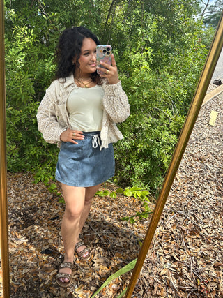 Ivory floral button-up jacket with puffed sleeves, paired with cream top and denim skirt.
