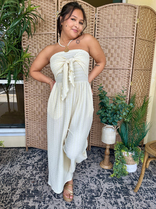 Cream striped strapless jumpsuit with tie-front detail and wide-leg silhouette.
