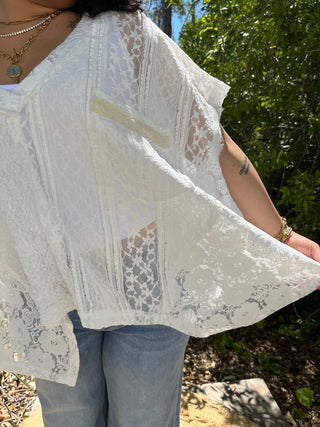 White lace short-sleeve handkerchief top with floral crochet pattern and sheer fabric.
