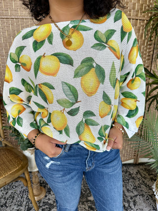 White batwing sweater with yellow lemons and green leaves all-over print.
