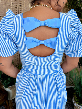 Blue and white striped midi dress with puff sleeves, cutout back detail, and bow embellishments.
