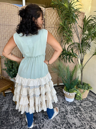 Light blue sleeveless dress with cream ruffled tiered skirt hem and drawstring waist.
